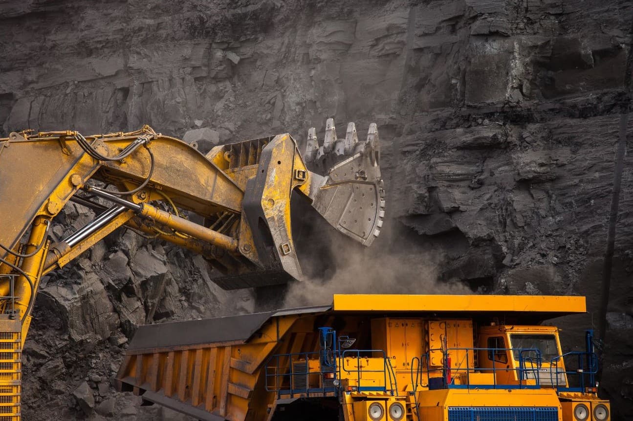 Mining excavator loading haul truck at open-pit site